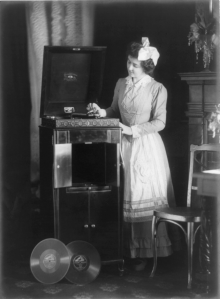 Woman in 1908 playing records on a Victrola phonograph.